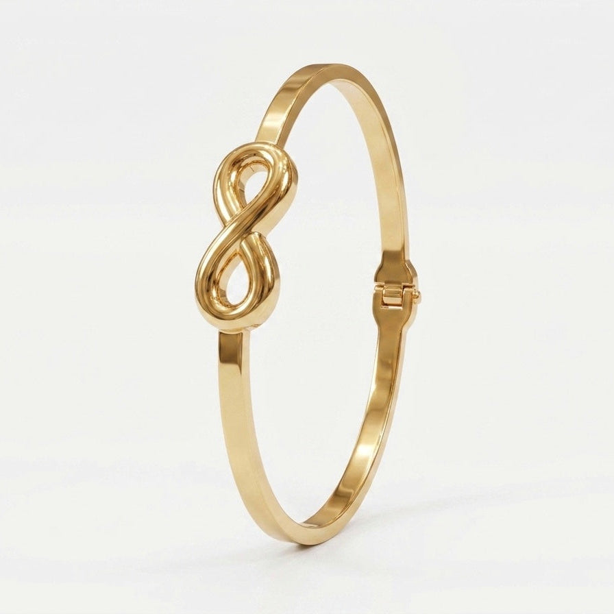 A polished gold bangle bracelet featuring a central infinity symbol, set against a clean white background.