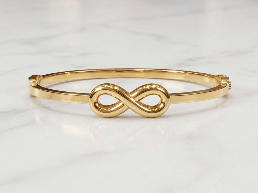 A polished gold bangle bracelet featuring a central infinity symbol