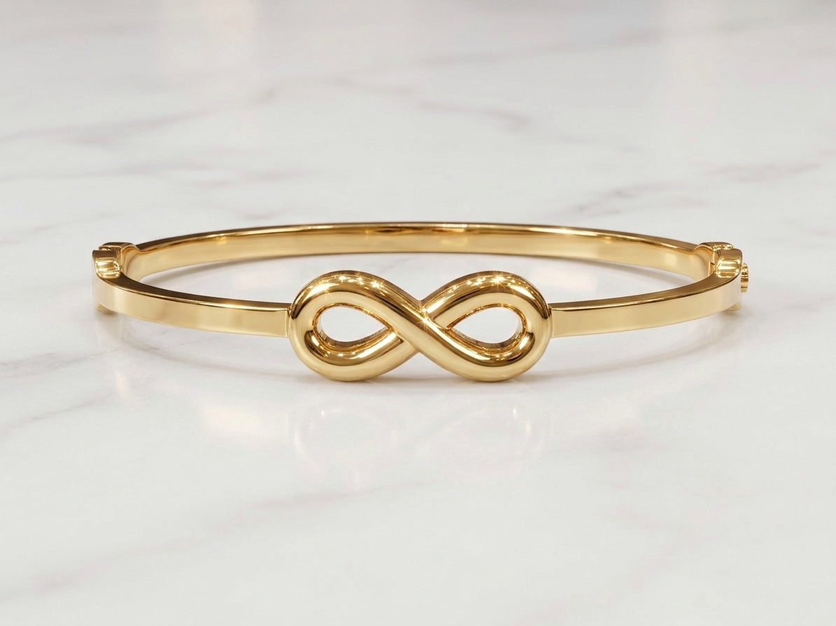 A polished gold bangle bracelet featuring a central infinity symbol