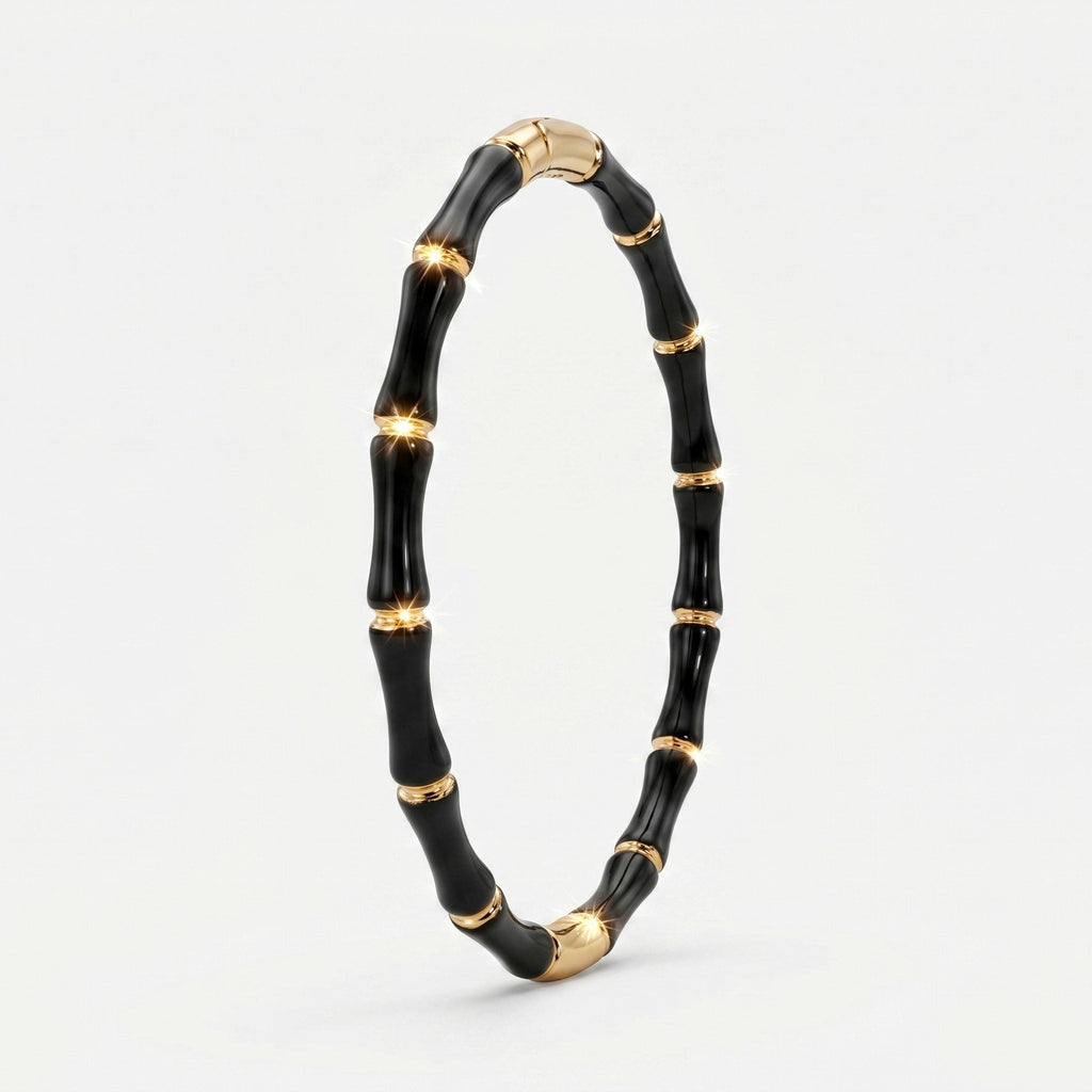 A black and gold bamboo-style bangle bracelet, standing upright on a clean white background.