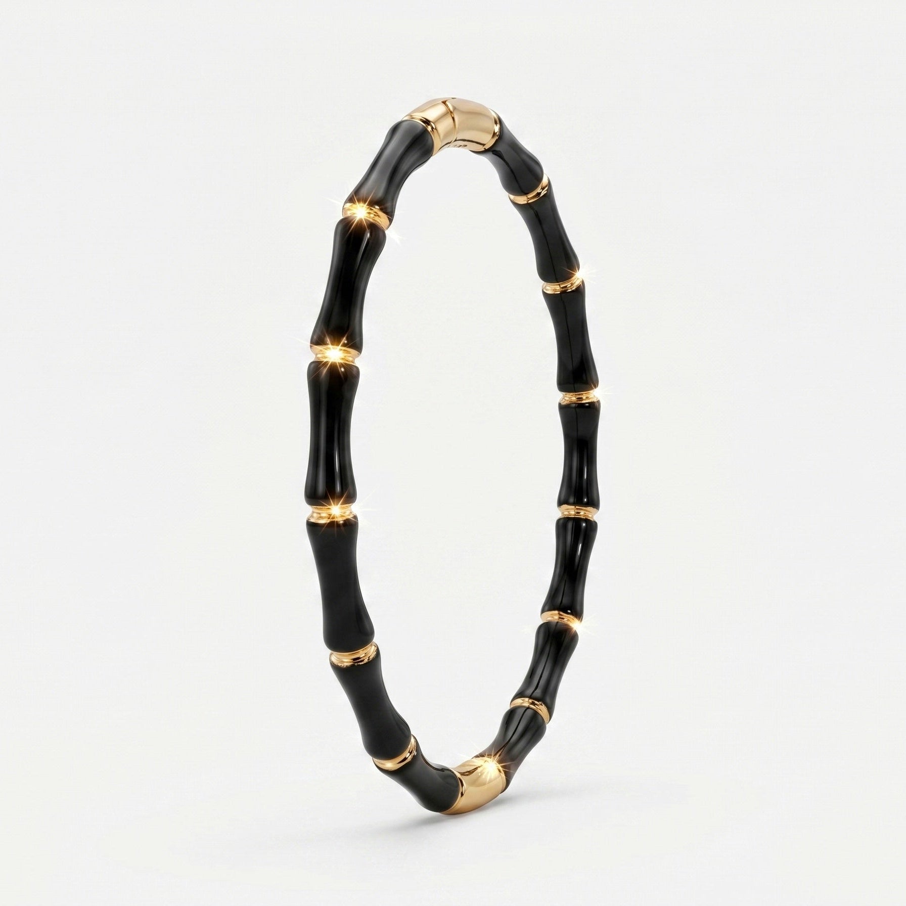 A black and gold bamboo-style bangle bracelet, standing upright on a clean white background.