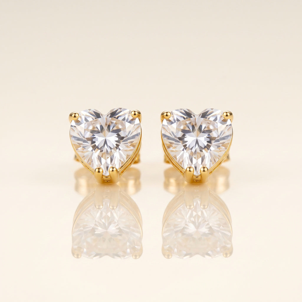 A pair of heart-shaped stud earrings with clear faceted gemstones in gold prong settings