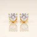 A pair of heart-shaped stud earrings with clear faceted gemstones in gold prong settings
