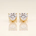 A pair of heart-shaped stud earrings with clear faceted gemstones in gold prong settings