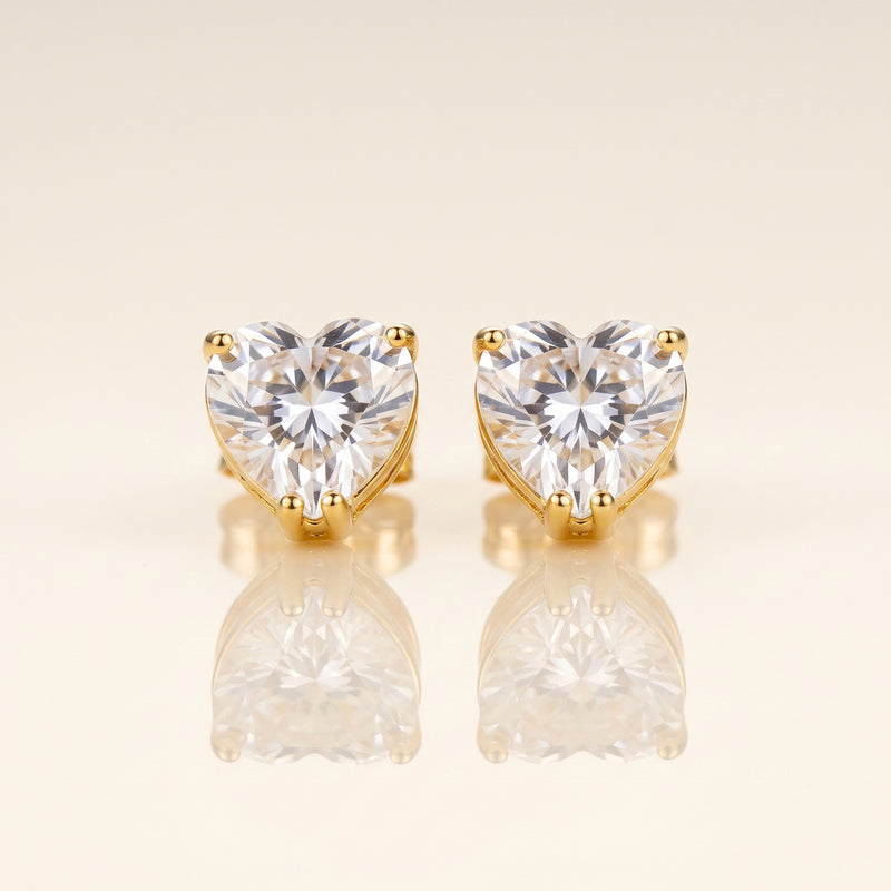 A pair of heart-shaped stud earrings with clear faceted gemstones in gold prong settings