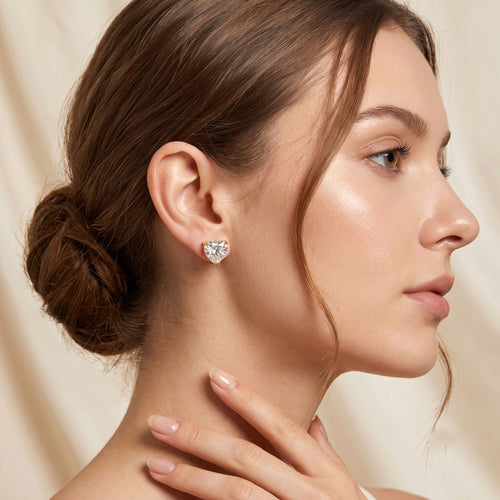 A pair of heart-shaped stud earrings with clear faceted gemstones in gold prong settings