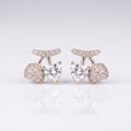 A pair of silver-toned stud earrings featuring a central heart-shaped clear gemstone, flanked by round pavé-set clear stones and a curved pavé top bar, 