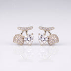 A pair of silver-toned stud earrings featuring a central heart-shaped clear gemstone, flanked by round pavé-set clear stones and a curved pavé top bar, 
