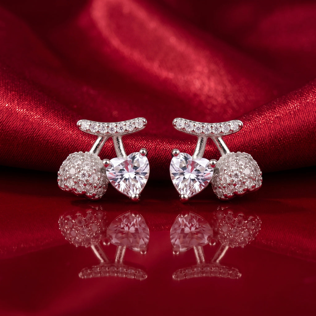 A pair of silver-toned stud earrings featuring a central heart-shaped clear gemstone, flanked by round pavé-set clear stones and a curved pavé top bar