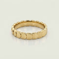 A gold band ring with a continuous scalloped or wavy textured edge, 
