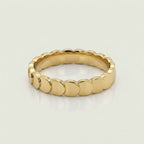 A gold band ring with a continuous scalloped or wavy textured edge, 