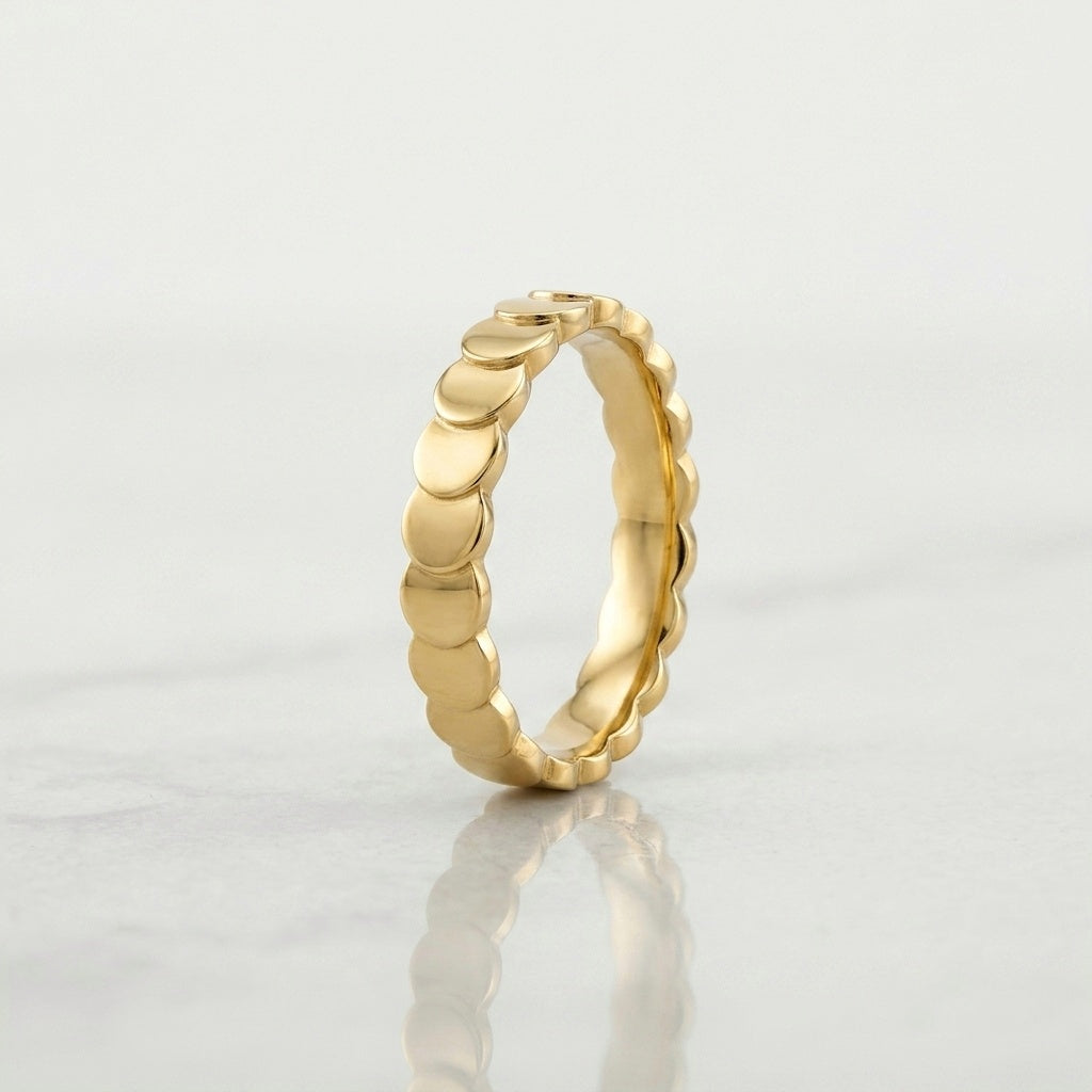 A gold band ring with a continuous scalloped or wavy textured edge, 