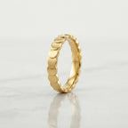 A gold band ring with a continuous scalloped or wavy textured edge, 