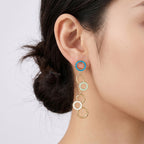 A pair of gold-tone dangle earrings with circular enamel details in blue, pale green, and white
