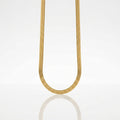 A gold snake chain necklace suspended in a U-shape against a clean white background with a soft reflection below.