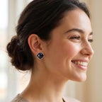 A woman with her hair in a low bun is shown in profile, wearing a small geometric stud earring with a dark blue-gray center and a silver-toned border.