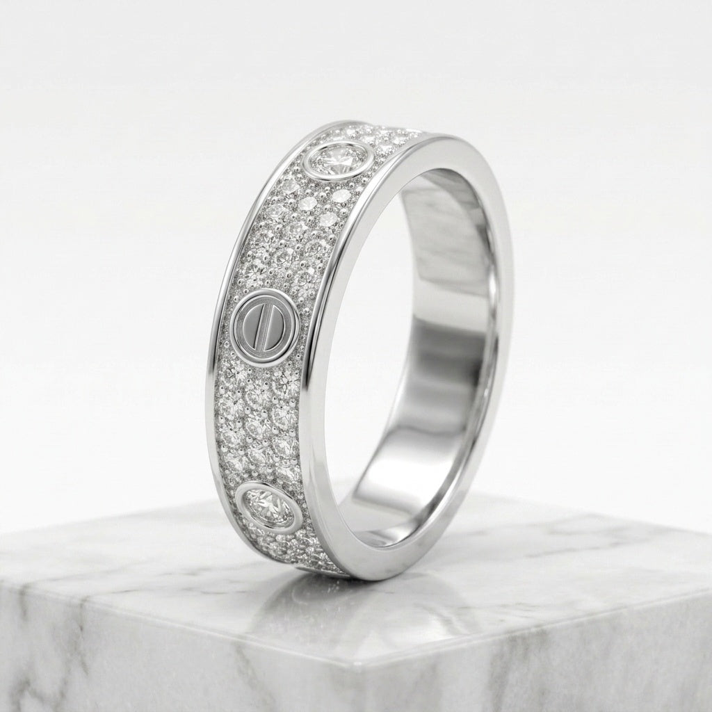 A silver-tone diamond band ring with screw-head details, displayed on a white marble block against a clean white background.