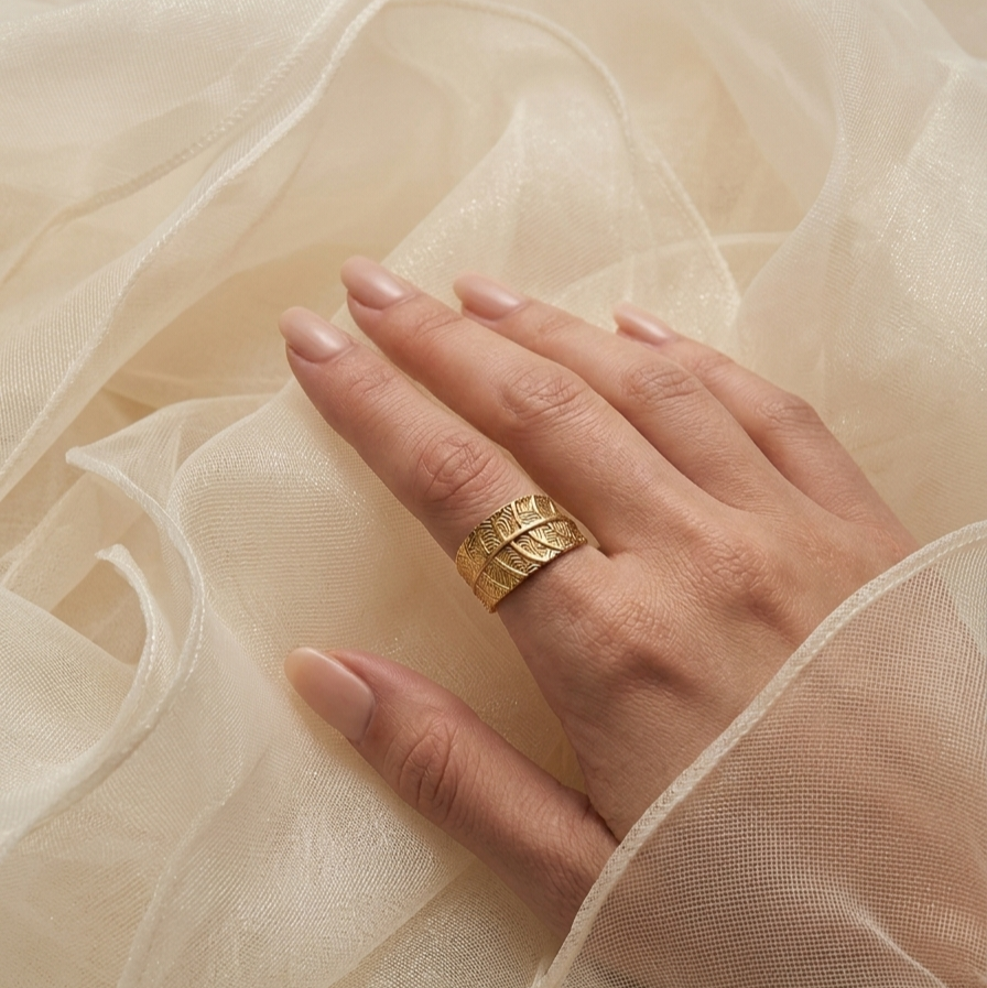 Hand wearing a gold leaf pattern ring 