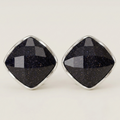 A pair of diamond-shaped stud earrings featuring faceted black stone with subtle gold speckles, set in polished silver-tone metal bezels, on a light cream background.
