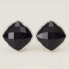 A pair of diamond-shaped stud earrings featuring faceted black stone with subtle gold speckles, set in polished silver-tone metal bezels, on a light cream background.
