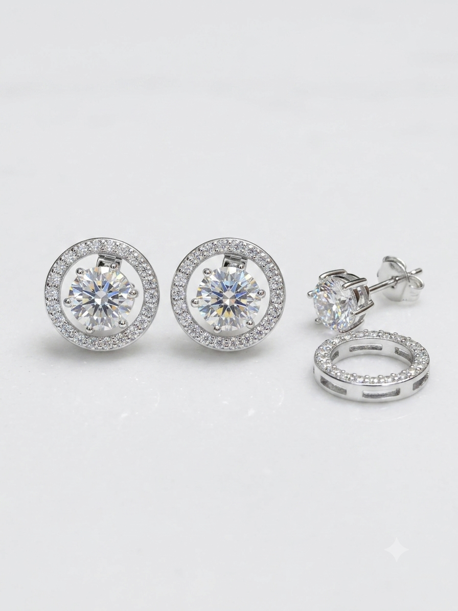 Silver-tone stud earrings with round-cut clear center stones surrounded by a halo of smaller clear stones, shown on a clean white background with one earring displayed front-on and another showing the side/back detail.