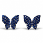 A pair of butterfly-shaped stud earrings paved with deep blue gemstones in a silver-tone setting, shown against a plain white background.