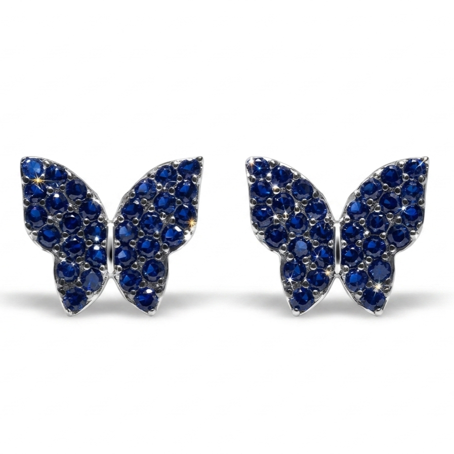 A pair of butterfly-shaped stud earrings paved with deep blue gemstones in a silver-tone setting, shown against a plain white background.