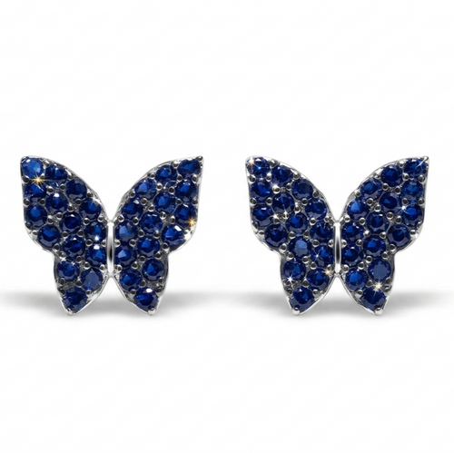 A pair of butterfly-shaped stud earrings paved with deep blue gemstones in a silver-tone setting, shown against a plain white background.