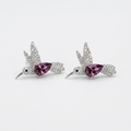 A pair of silver-toned bird stud earrings with sparkling clear stones and a central teardrop-shaped pink gemstone, displayed on a clean white background.