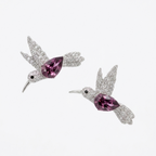 A pair of silver-toned hummingbird stud earrings paved with clear stones, featuring a central marquise-cut pink gemstone, shown on a plain white background.