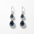 A pair of silver drop earrings featuring pear-shaped dark blue gemstones surrounded by small clear stones, shown on a clean white background.
