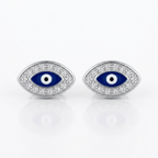 A pair of silver-toned evil eye stud earrings with blue enamel and white accents, set with small clear stones, on a white reflective background.