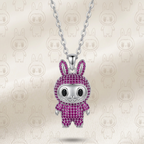 A silver bunny pendant necklace covered in pink rhinestones, hanging from a silver chain against a light beige background with a faint repeating bunny pattern.