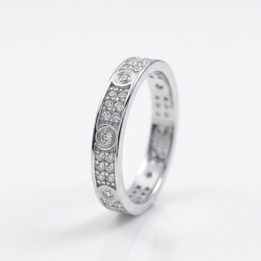 A silver-toned eternity ring featuring rows of small clear pavé stones with three larger round-cut center stones, photographed on a clean white background.