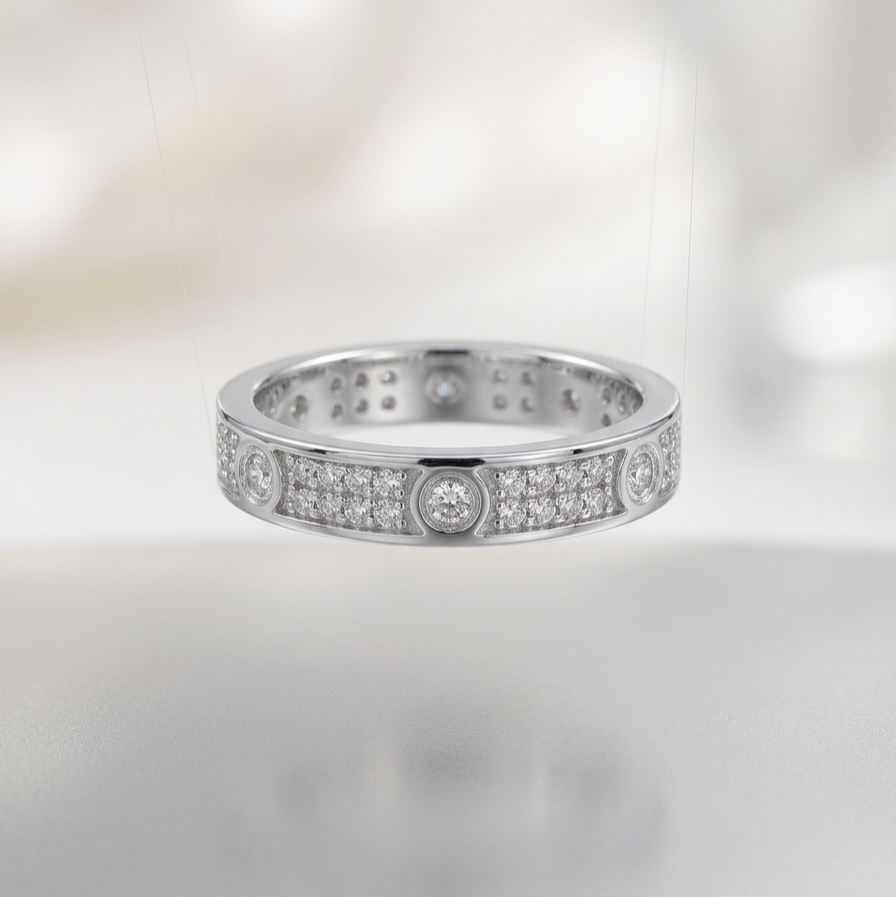 A silver-toned eternity ring set with round diamonds, suspended against a soft, out-of-focus white background.