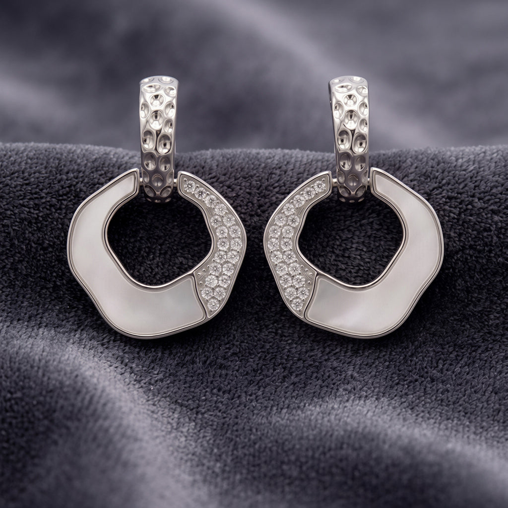 Pair of silver hoop earrings with black center on a textured gray surface