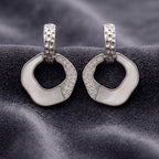 Pair of silver hoop earrings with black center on a textured gray surface