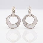 Pair of silver hoop earrings with gemstones on a light gray background