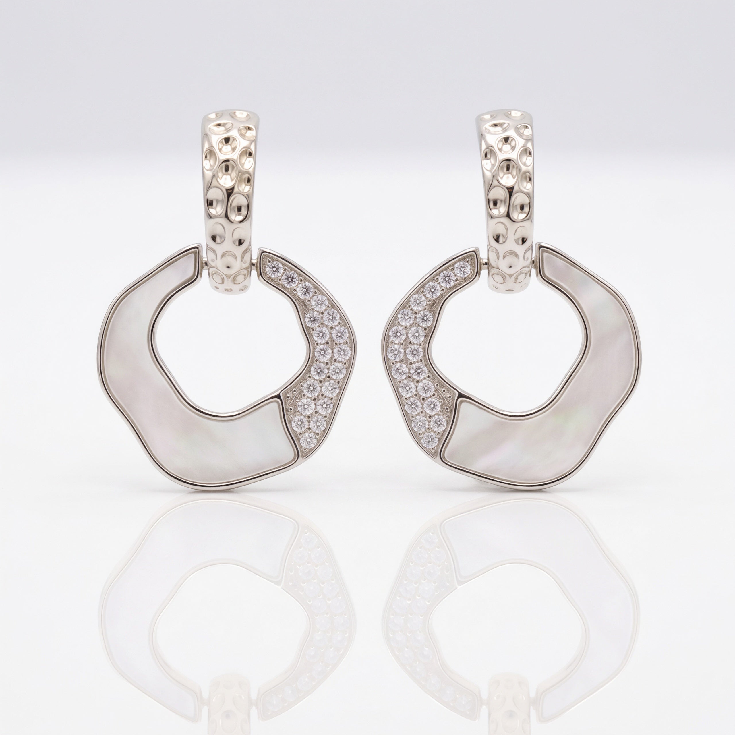 Pair of silver hoop earrings with gemstones on a light gray background