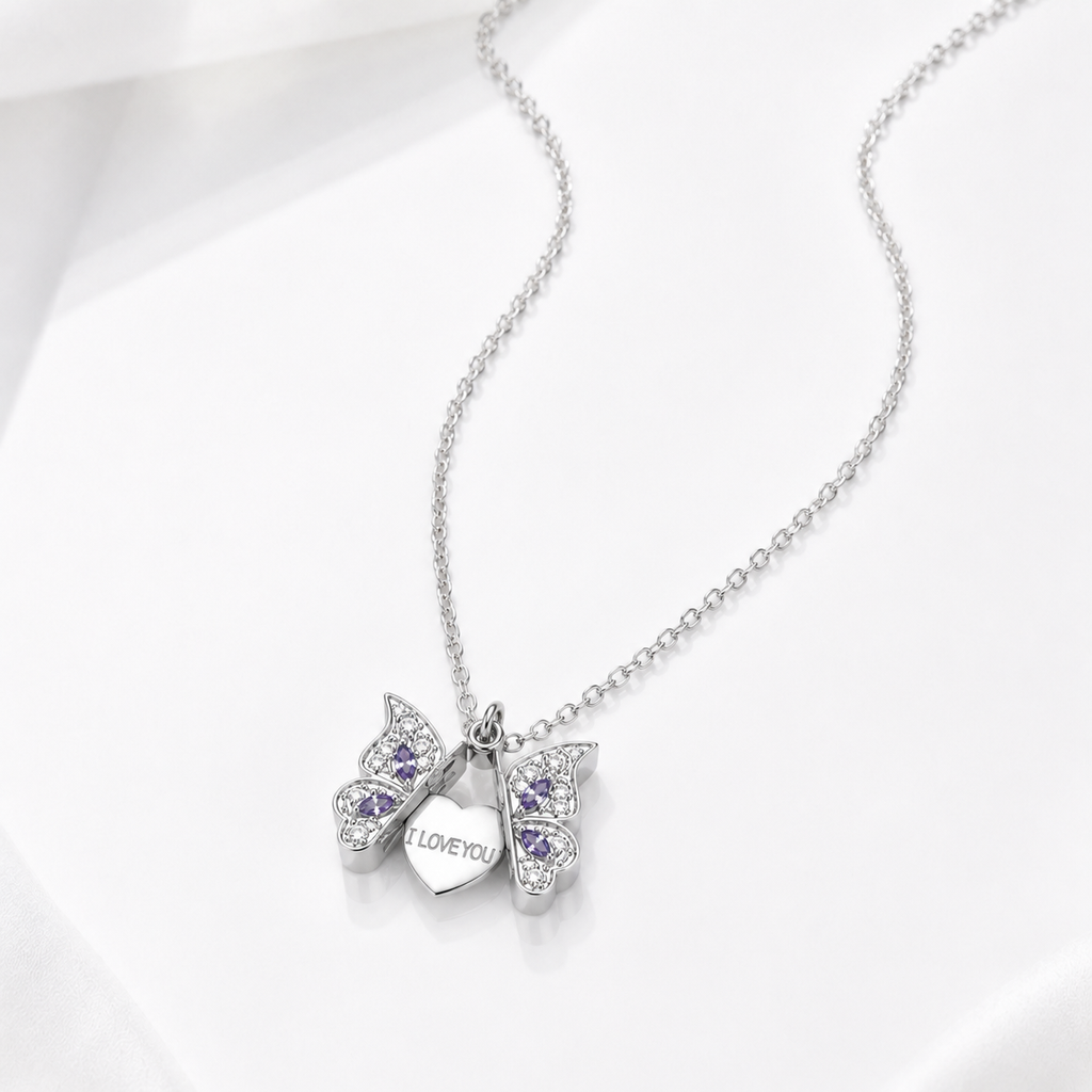 A silver butterfly pendant necklace with purple gemstone accents and a small heart charm engraved with 'I LOVE YOU', displayed on a clean white background.