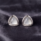 Pair of silver earrings with triangular gemstones on a dark fabric background