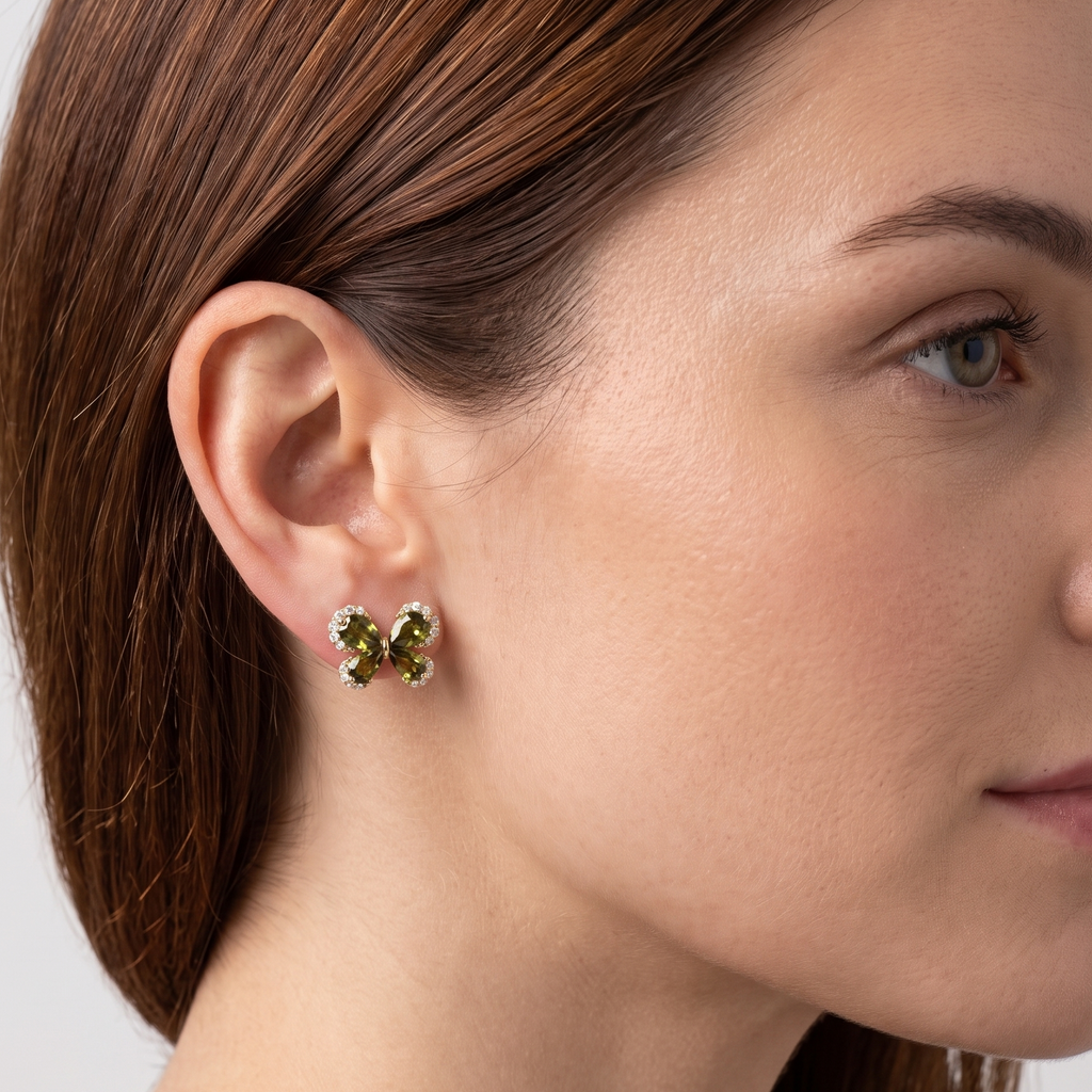 Close-up of a woman wearing green gemstone earrings with a neutral background