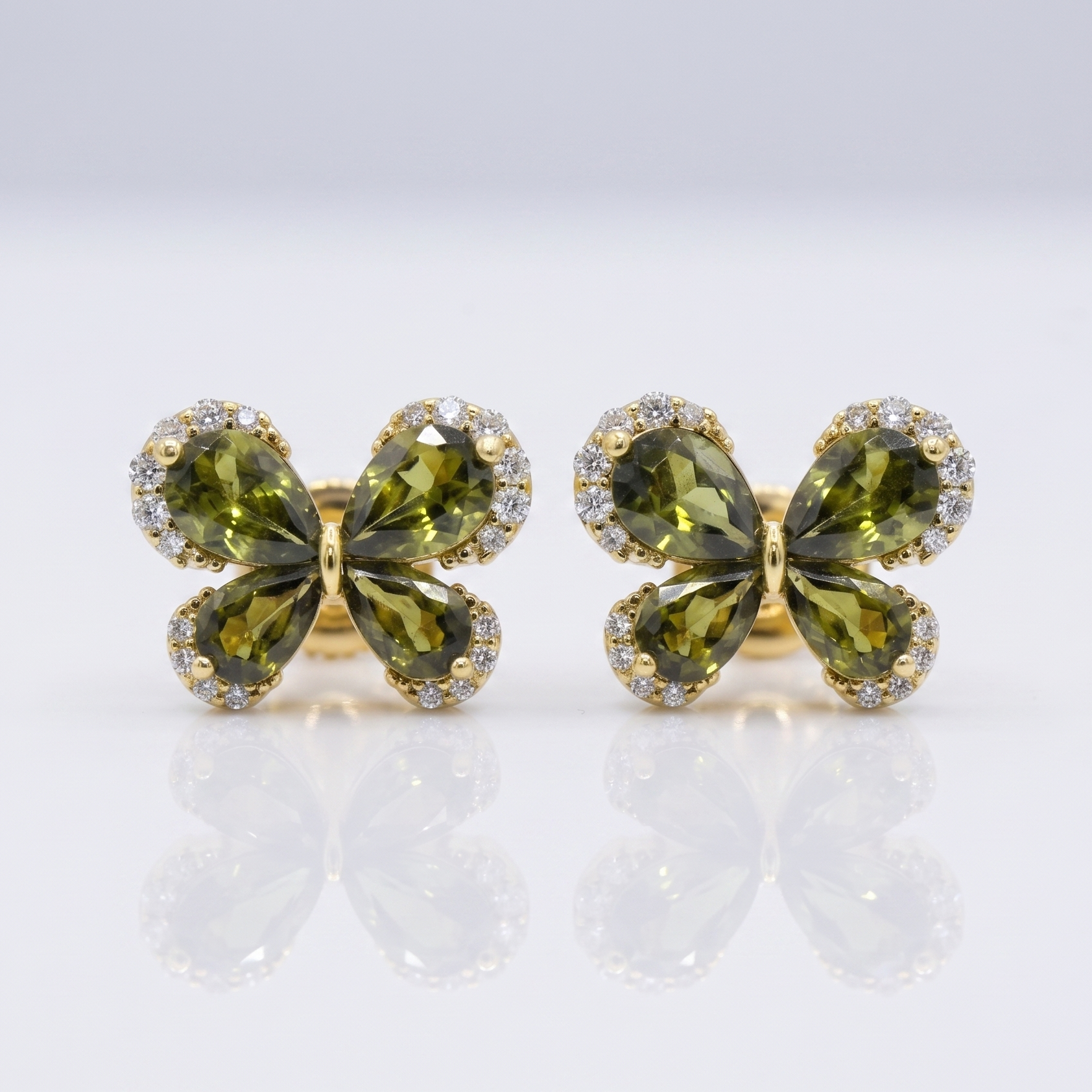 Pair of green butterfly-shaped earrings with gold accents on a white background