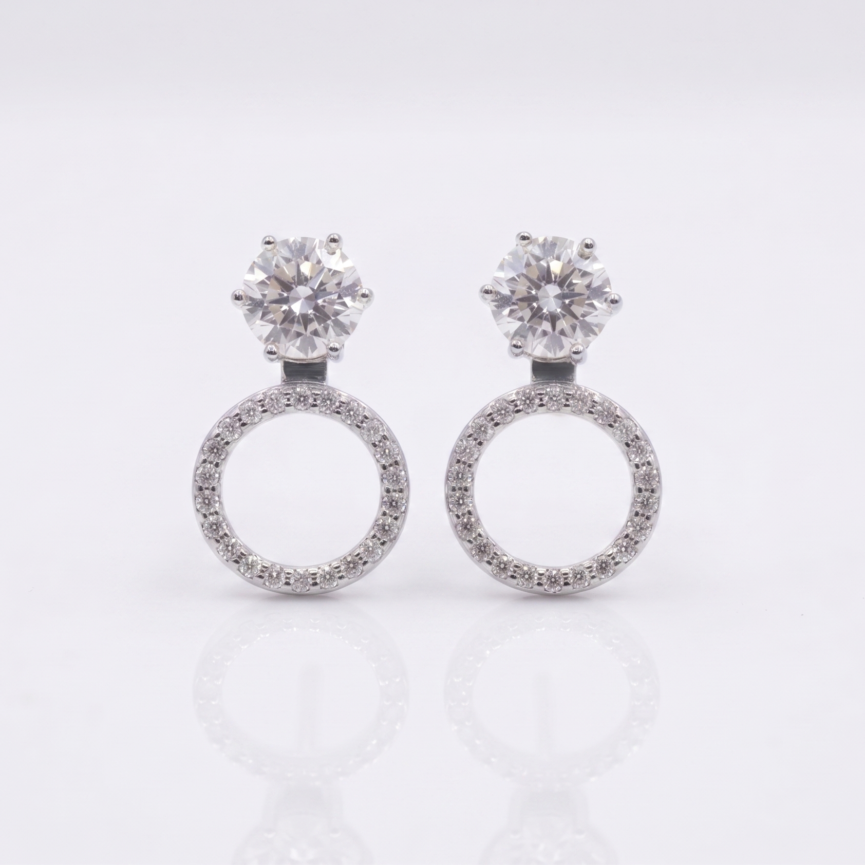 Pair of silver earrings with circular designs on a light gray background