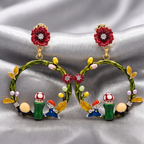 Pair of earrings with cartoon character design on a silver fabric background