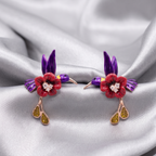 Pair of earrings with floral and bird design on a satin background