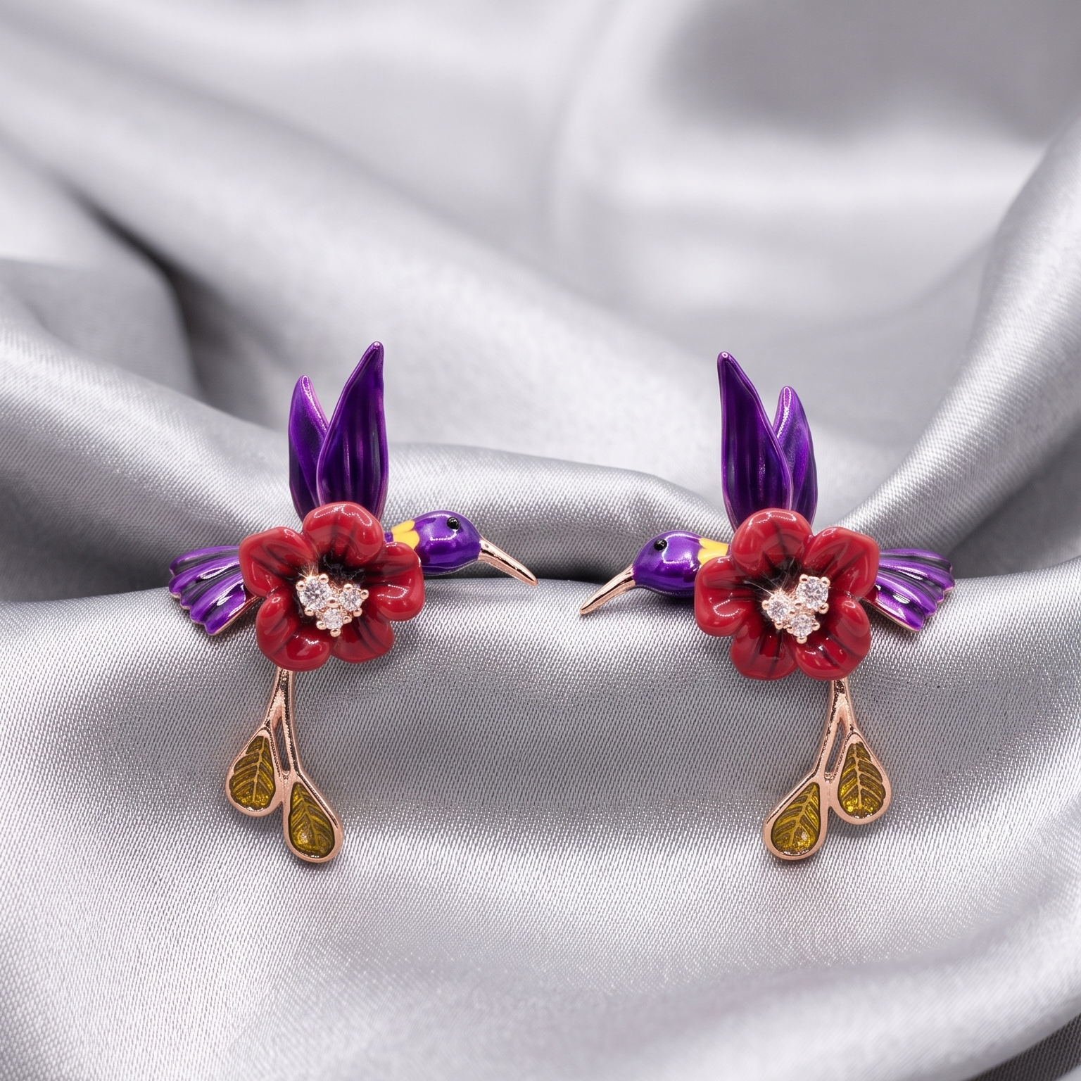 Pair of earrings with floral and bird design on a satin background