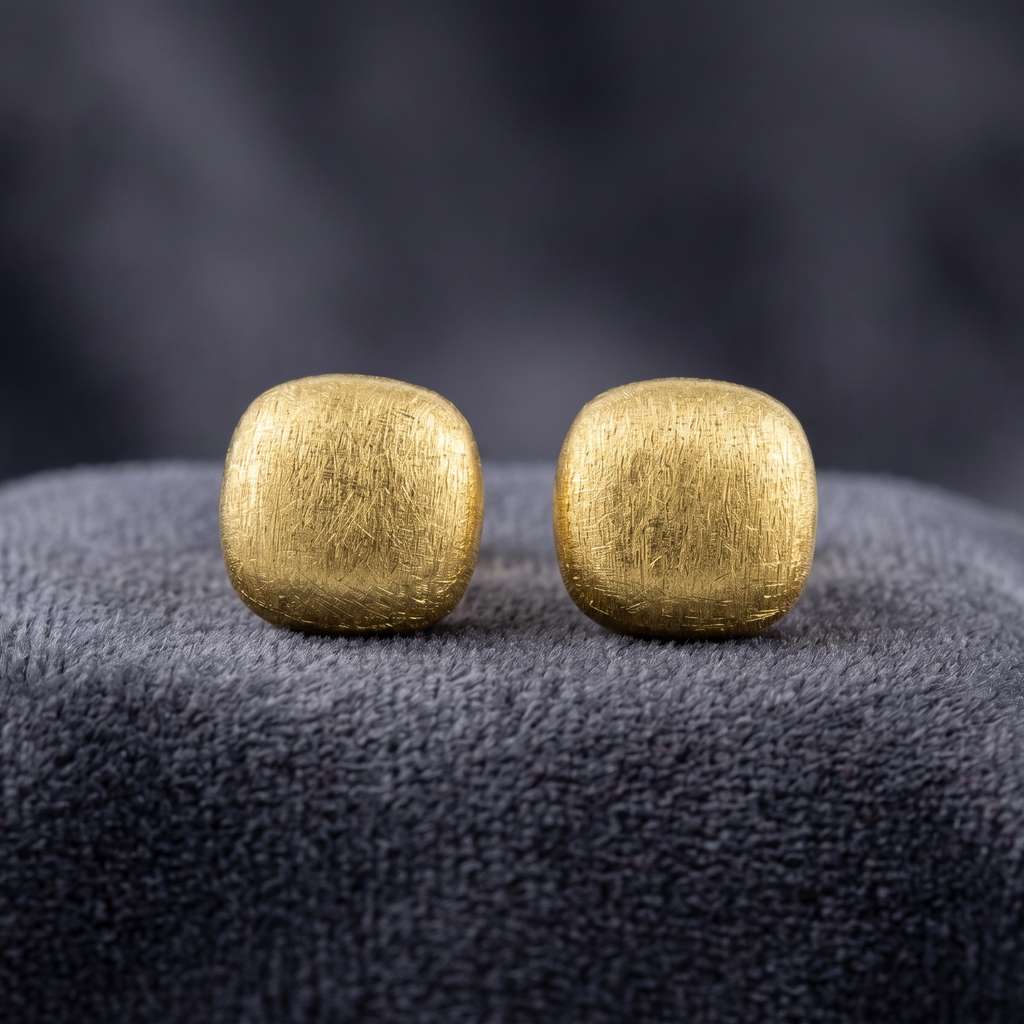 Pair of gold square earrings on a dark textured surface