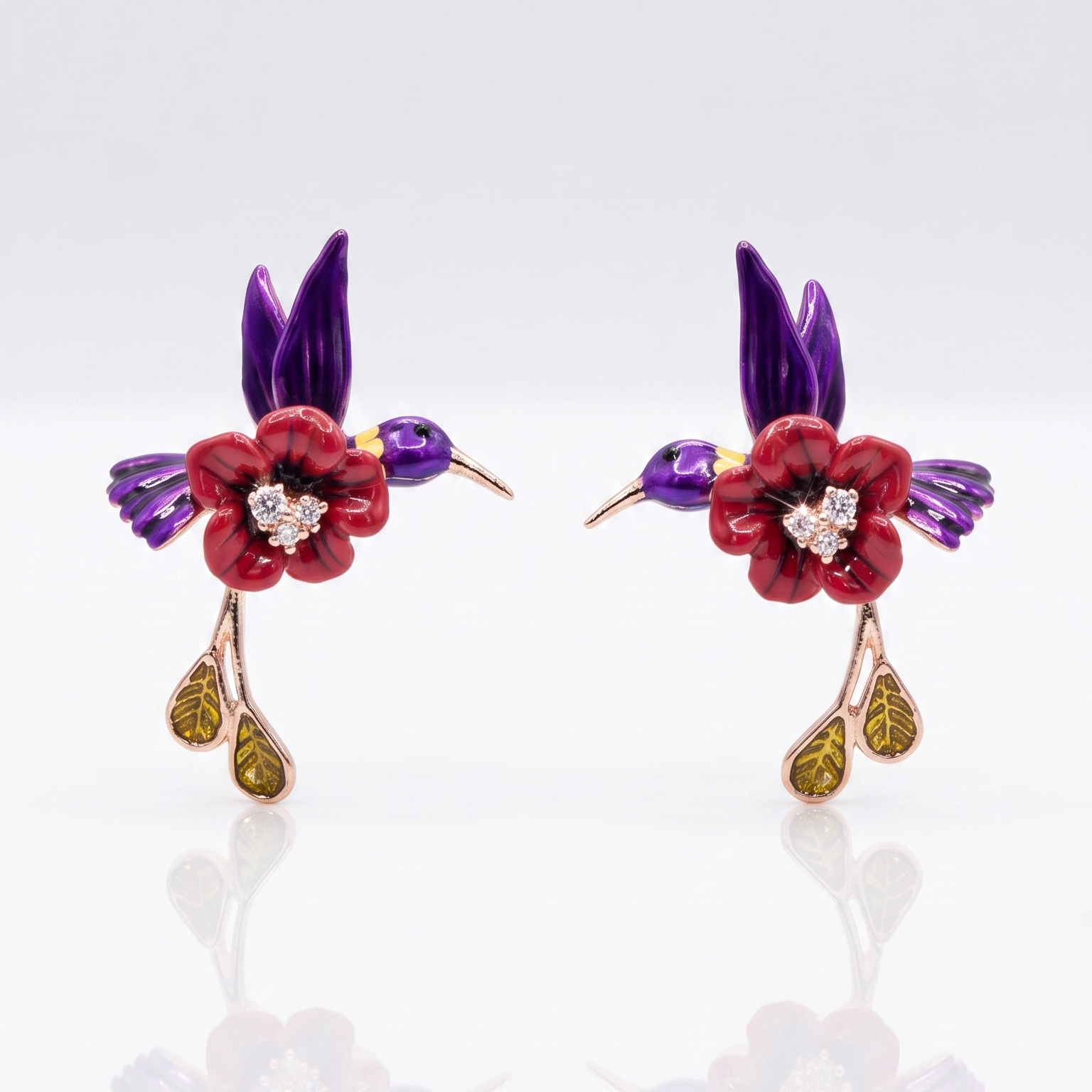 Pair of floral earrings with red flowers, purple leaves, and gold accents on a white background