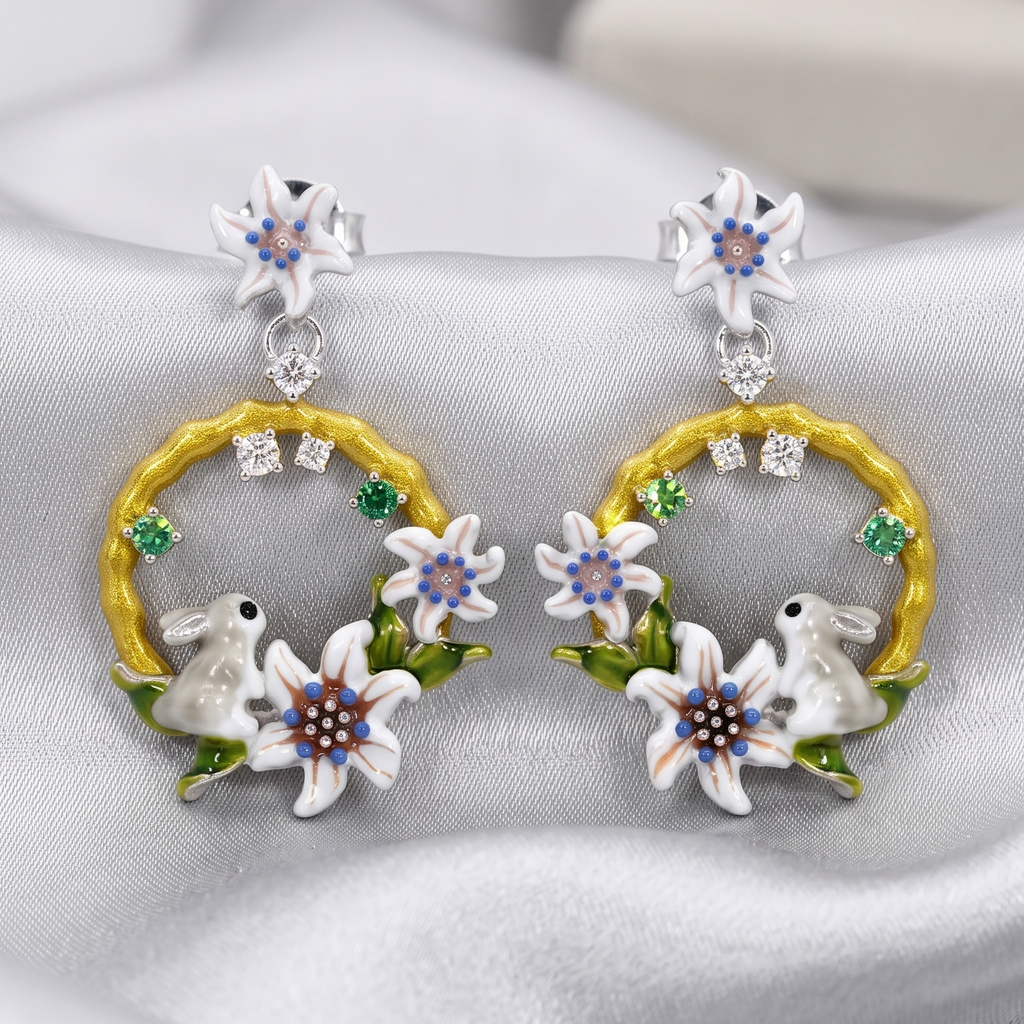 Pair of earrings with floral and rabbit design on a gray background